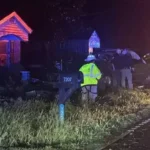 Law enforcement and emergency responders at a crash scene after a truck hit a house