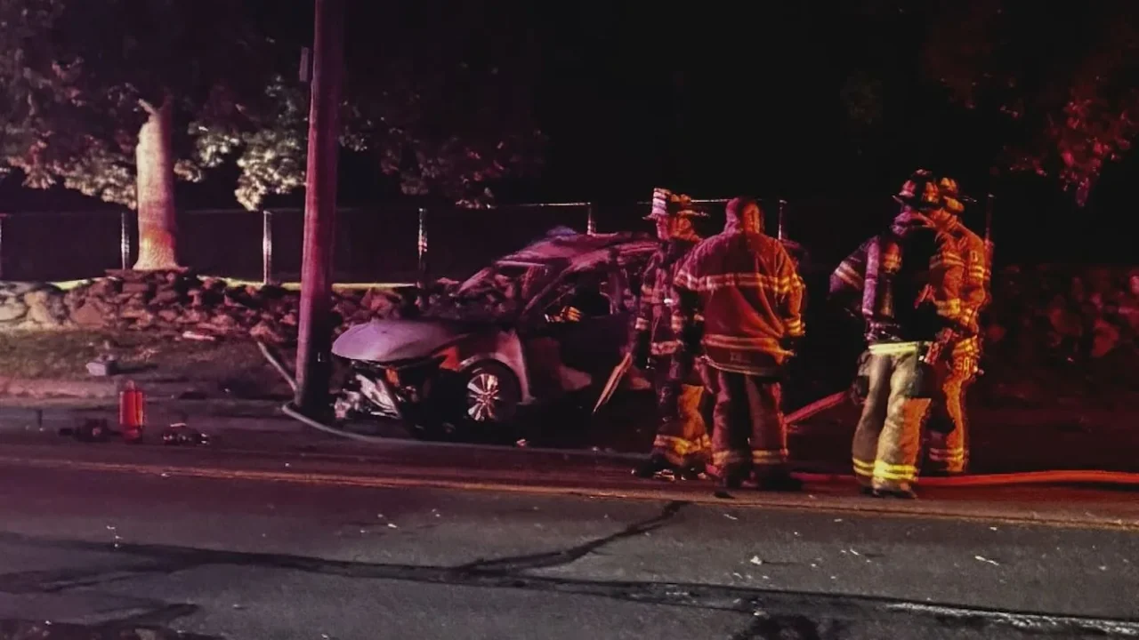 Damaged car wreckage near a utility pole and stone wall after a fatal Middletown crash