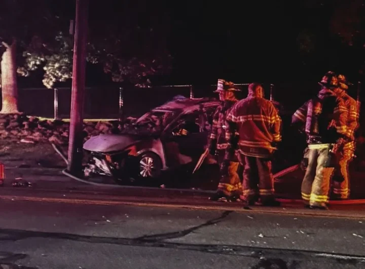 Damaged car wreckage near a utility pole and stone wall after a fatal Middletown crash